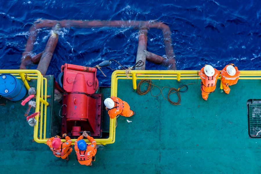 Offshore workers working together during anchor handling job on a construction barge at oil field